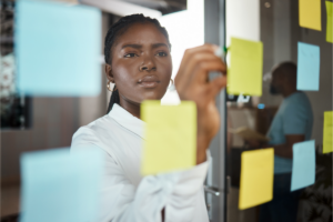 Professional arranging sticky notes on a glass wall during a planning session.