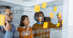 A group of colleagues brainstorming against a clear board.